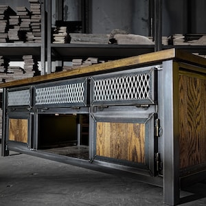 May include: A large, industrial-style cabinet with a metal frame and wooden accents. The cabinet features a light-colored wood top, metal mesh drawer fronts, and wooden door panels. The overall design is a blend of rustic and modern aesthetics.