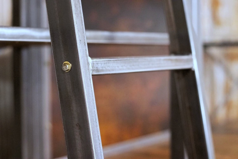 May include: Close-up of a metal shelf unit with a brass screw. The shelf unit is made of black metal with a brushed finish.