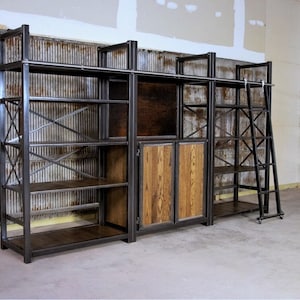 May include: A large, industrial-style shelving unit with a ladder. The shelves are made of metal and wood, and the unit has a rustic look. The unit is made up of three sections, with the middle section having two doors.