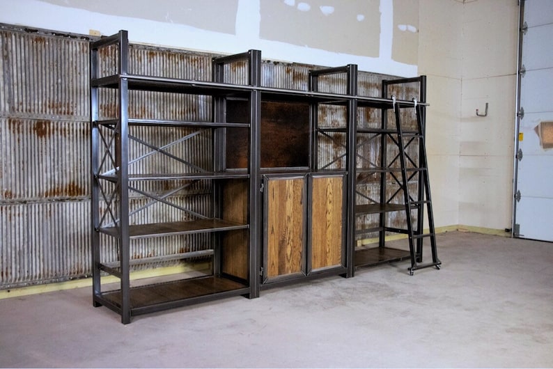 May include: A large, industrial-style shelving unit with a ladder. The shelves are made of metal and wood, and the unit has a rustic look. The unit is made up of three sections, with the middle section having two doors.