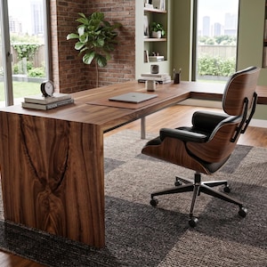 Op de afbeelding: Een L-vormig bureau van donker walnoothout met een zichtbare houtnerf, inclusief een bijpassende draaibare bureaustoel met een gebogen walnoothouten schaal, zwarte lederen bekleding en een metalen onderstel met vijf wieltjes.