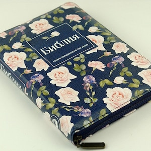 May include: A blue zippered case with a floral pattern of pink roses and purple irises. The case has the word "Библия" (Biblia) and the text "книги священного писания" (books of holy scripture) printed on the front.