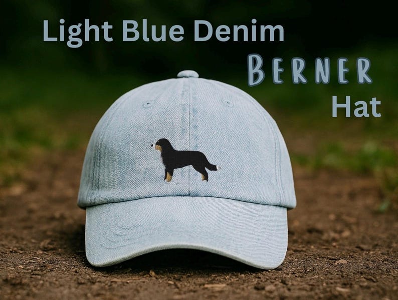 May include: A light blue denim baseball cap featuring an embroidered Bernese Mountain Dog on the front panel. The text Light Blue Denim BERNER Hat is printed in the upper portion of the frame. The cap has a curved brim and a structured crown.