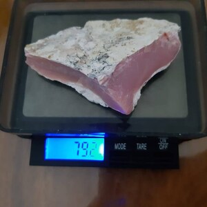 Op de afbeelding: Een roze en witte opaal steen op een digitale weegschaal. De weegschaal geeft 7,92 aan.