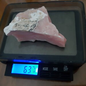 Pode incluir: Uma gema de opala rosa em uma balan&ccedil;a digital, pesando 6,37 gramas.