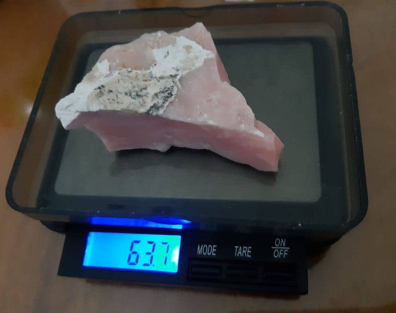 Pode incluir: Uma gema de opala rosa em uma balan&ccedil;a digital, pesando 6,37 gramas.