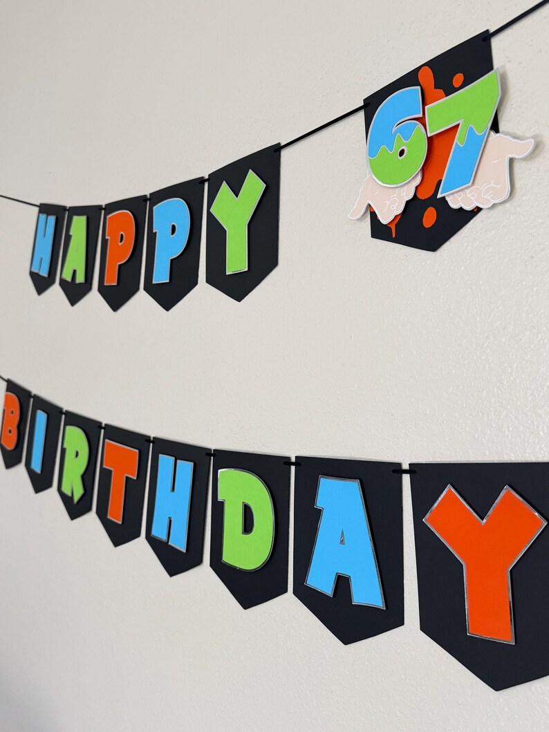 May include: A black banner with the words "HAPPY BIRTHDAY" in colorful letters. The letters are outlined in silver and have a 3D effect. A separate banner displays the number "67" with a splatter design.