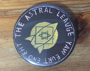 The Astral Leauge 58mm (2 1/4") pin button badge featuring Brian Parker art