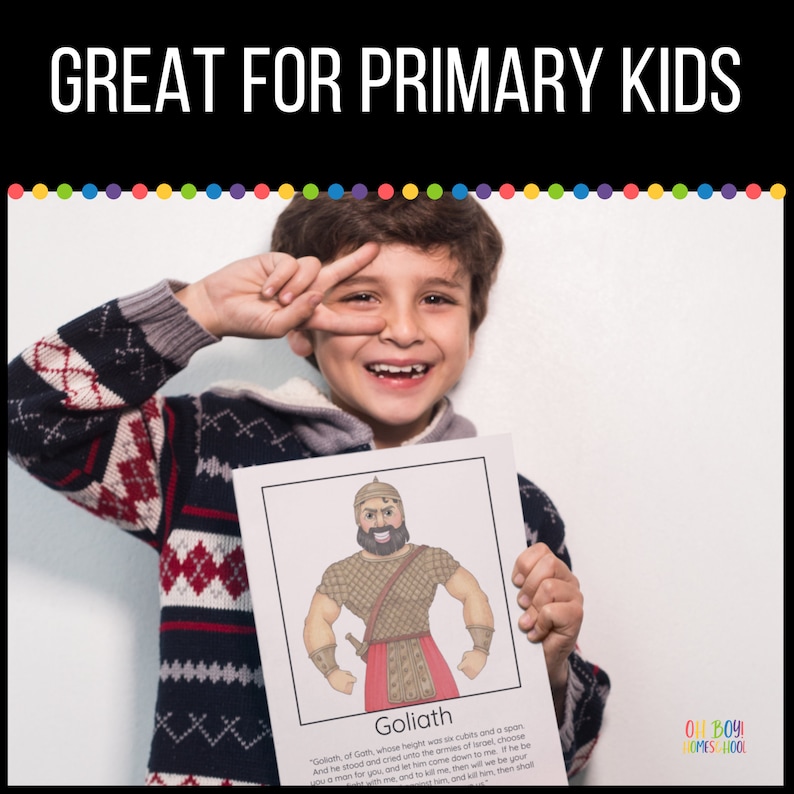 May include: A young boy holds up a printable educational card featuring a cartoon illustration of Goliath from the Bible. The card has the text "Goliath" and a quote about Goliath's height and challenge to the Israelites. The card is part of a set for primary school children.