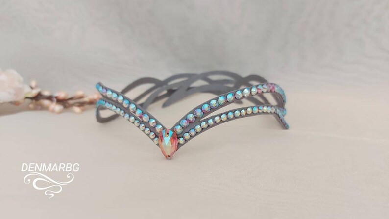 May include: A gray headband with two rows of iridescent rhinestones and a larger iridescent rhinestone in the center.