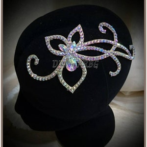 Puede incluir: Una pieza de pelo de pedrería plateada con un diseño floral y un patrón de espiral. La pieza de pelo está en una cabeza de maniquí de terciopelo negro.