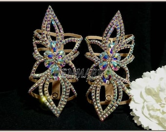 May include: A pair of beige dance shoe embellishments with a floral design. The embellishments are covered in iridescent rhinestones.