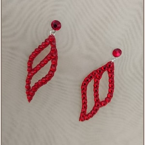 May include: A pair of red crystal earrings shaped like a leaf with a silver post.