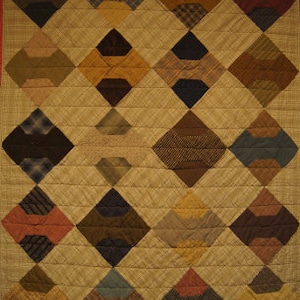 May include: A quilt with a diamond pattern made from various fabrics in shades of brown, blue, red, and yellow. The quilt is quilted with a simple stitch pattern.