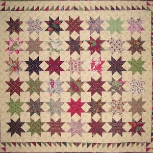 May include: A beige quilt with a patchwork design featuring a variety of floral and geometric patterns. The quilt is made up of a grid of 36 stars, each with a different fabric. The stars are surrounded by a border of beige fabric with a scalloped edge.