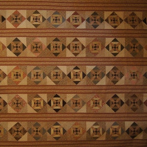 May include: A quilt with a repeating pattern of brown, beige, and white squares. The squares are arranged in a diamond pattern, creating a geometric design.