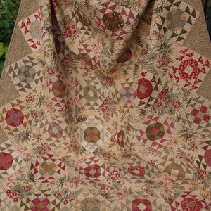 May include: A large quilt with a patchwork design featuring a variety of floral patterns in shades of brown, red, and white. The quilt is made up of squares and triangles, and the fabric is a mix of textures and patterns.