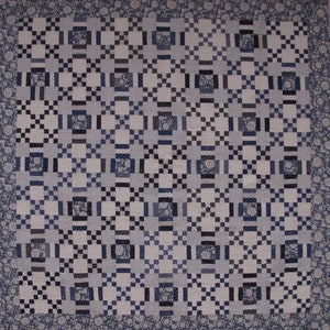May include: A quilt with a geometric pattern in shades of blue and white. The quilt is made up of squares and rectangles, and the pattern is created by the way the squares and rectangles are sewn together.