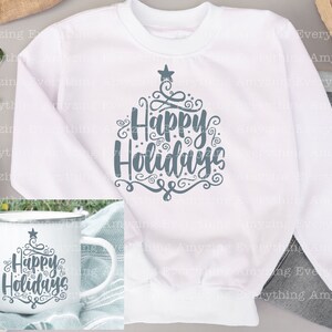 May include: White sweatshirt with a grey design of a stylised Christmas tree with the text "Happy Holidays". A white mug with the same design is shown in the bottom left corner.