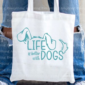May include: White tote bag with a teal blue graphic that says "Life is better with dogs". The graphic includes a stylized dog with its tail curled up.