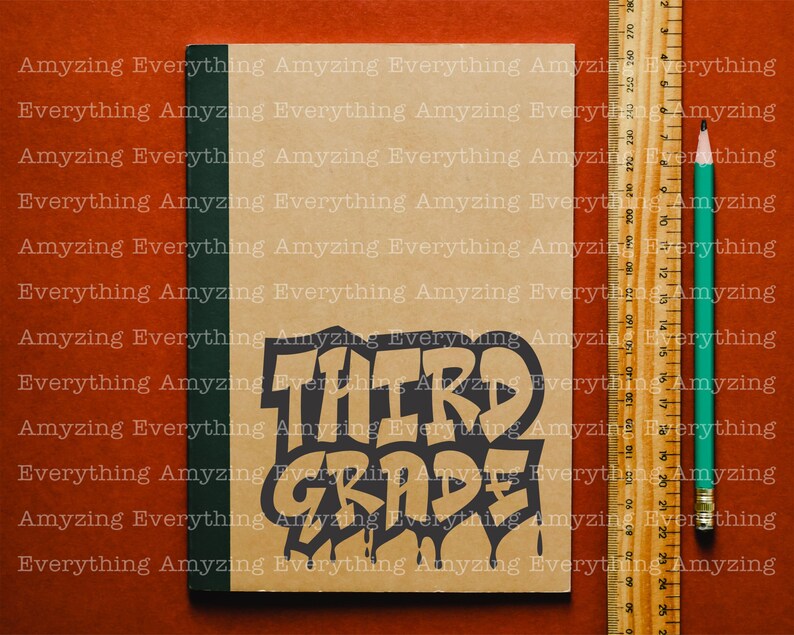 May include: A brown notebook with a black and white sticker that says "THIRD GRADE" in a dripping paint style. The notebook is on a red surface with a green pencil and a wooden ruler.