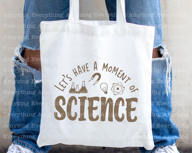 Może przedstawiać: Biała torba typu tote z brązowym tekstem, kt&oacute;ry brzmi "Let's have a moment of science". Tekst jest otoczony obrazami zlewki, żar&oacute;wki, magnesu i atomu.