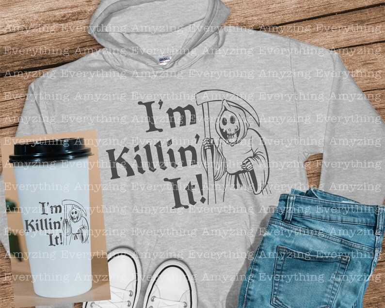 May include: A gray hoodie with a black graphic of a skeleton holding a scythe and the text "I'm Killin' It!"  A white coffee mug with the same graphic is also shown.