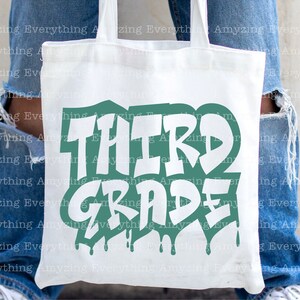 May include: White tote bag with a green and white graphic that says "Third Grade". The graphic has a dripping paint effect.