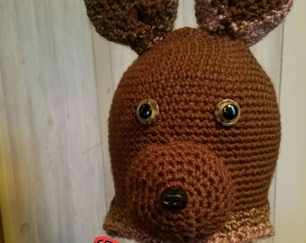 May include: Brown crocheted bear hat with a long scarf. The hat has large ears and black button eyes. The scarf is brown and pink.