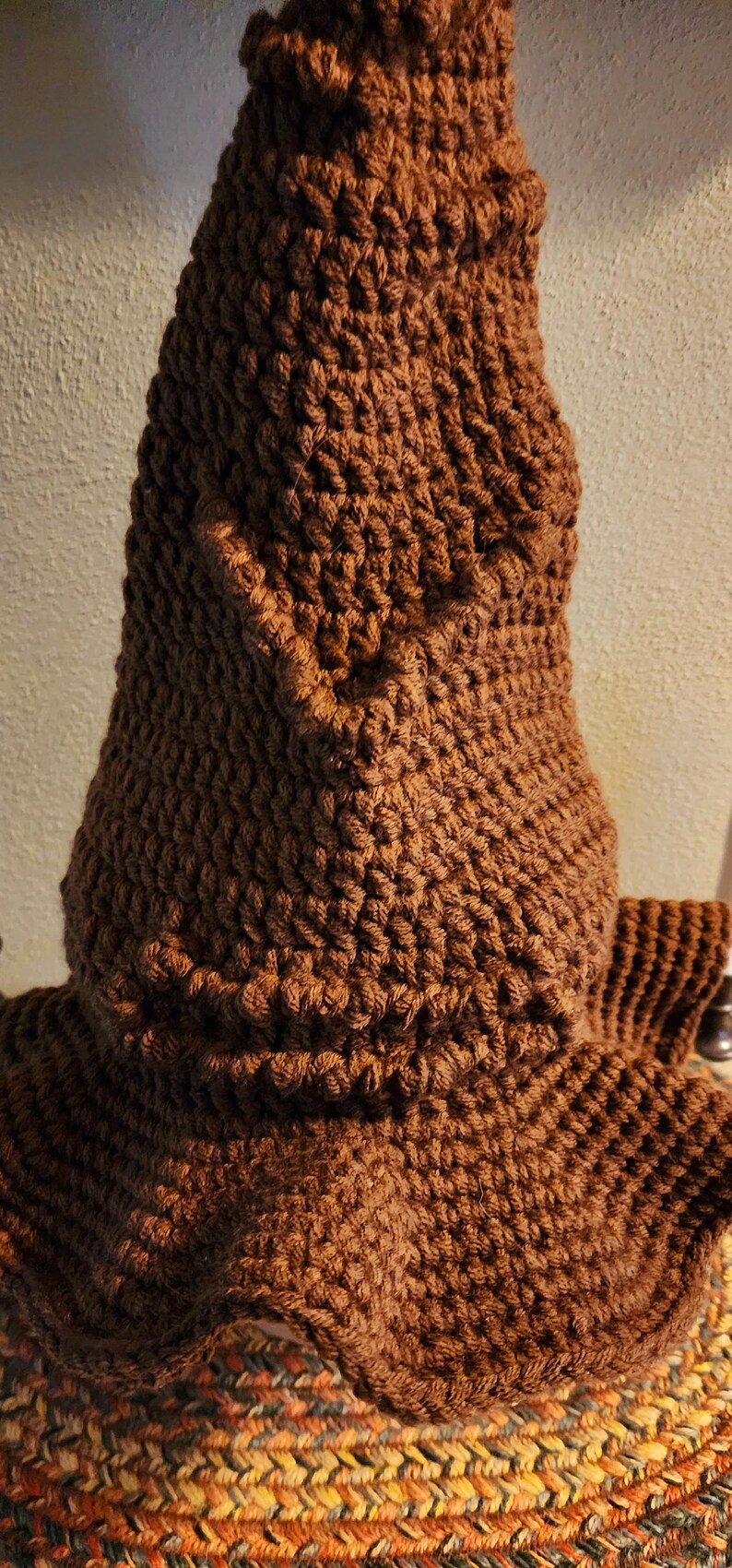 May include: A handmade, brown crocheted hat with a pointed top and a textured, woven appearance. The hat has a wide brim and is made of a soft, warm material, perfect for cold weather. The hat is a unique, handcrafted item.