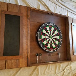 Beautiful Custom hand made dart board cabinet, dart brd  knobs, crafted in our wood  shop, with chaulk tray at bottom approximately 28"×28"