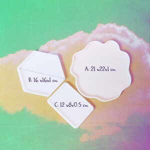 Puede incluir: Tres moldes de resina blanca para manualidades. Los moldes tienen forma de hexágono, nube y rectángulo. El molde hexagonal mide 16 cm por 16 cm por 1 cm. El molde en forma de nube mide 21 cm por 22 cm por 1 cm. El molde rectangular mide 12 cm por 8 cm por 0,5 cm.