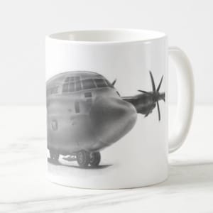 Peut inclure: Une tasse blanche avec une illustration en noir et blanc d'un avion C-130 Hercules. L'avion est en vol et porte l'inscription "US AIR FORCE" sur le côté.