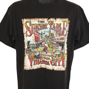 May include: Black t-shirt with a vintage-style graphic of a scene from Virginia City, Nevada. The graphic features the text "The Suicide Table" and "Virginia City".