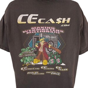 Może przedstawiać: Czarny T-shirt z kreskówkową ilustracją osoby trzymającej torbę z pieniędzmi i kij bejsbolowy. Na koszulce nadrukowany jest tekst "CECASH.COM MAKING WEBMASTERS MILLION$!". Tekst "CEVAULT" jest nadrukowany na sejfie za osobą. Tekst "AND COOL VAULT PRIZES TOO!" jest nadrukowany pod osobą. Tekst "CC LIFETIME CASH PAY IT FORWARD" jest nadrukowany pod stopami osoby. Tekst "CC MAILERS FOLLOW ME FREE" jest nadrukowany pod stopami osoby.