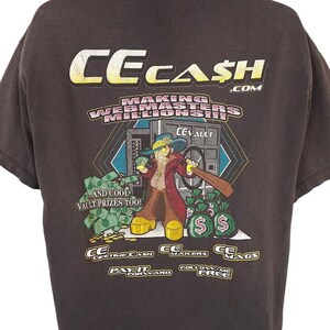 Może przedstawiać: Czarny T-shirt z kreskówkową ilustracją mężczyzny trzymającego worek pieniędzy. Tekst na koszulce brzmi "CECASH.COM MAKING WEBMASTERS MILLIONAIRES".