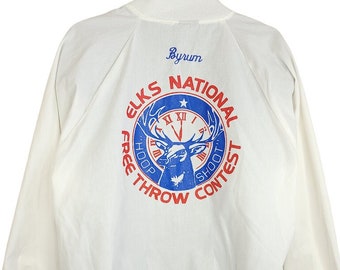 May include: White jacket with a blue and red circular logo on the back. The logo says "Elks National Free Throw Shoot Contest" and features a deer with antlers and a clock face.