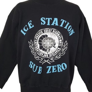May include: Black sweatshirt with a blue and white graphic print that says "ICE STATION SUB ZERO" and features a circular design with the text "EXP-PACIFIC COAST HIGHWAY-EXP" and a compass.