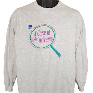May include: A gray long-sleeve t-shirt with a graphic of a magnifying glass and the text "A Case of Unfair Advantage" in a circle. The text "TokenLink III - LinkBuilder EMS" is also included in the circle.