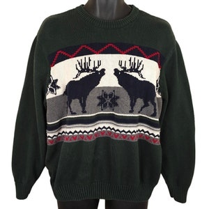 May include: A green sweater with a fair isle pattern featuring two elk, snowflakes, and red and white accents.