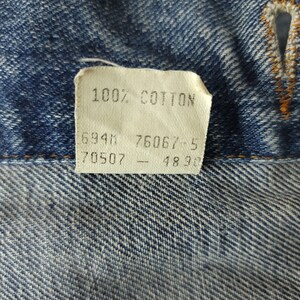 May include: A white tag with the text "100% COTTON" and numbers "6941", "7606", "70507", and "4896" printed on it.