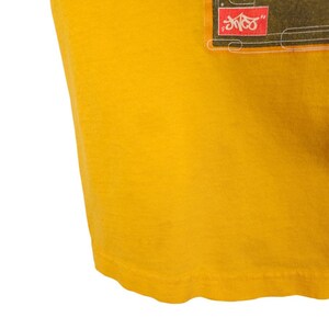 May include: A yellow t-shirt with a graphic print of a black and white image with the text "SHOCK" in red.
