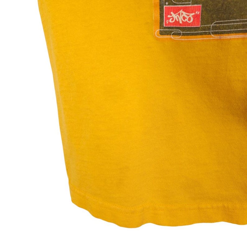 May include: A yellow t-shirt with a graphic print of a black and white image with the text "SHOCK" in red.