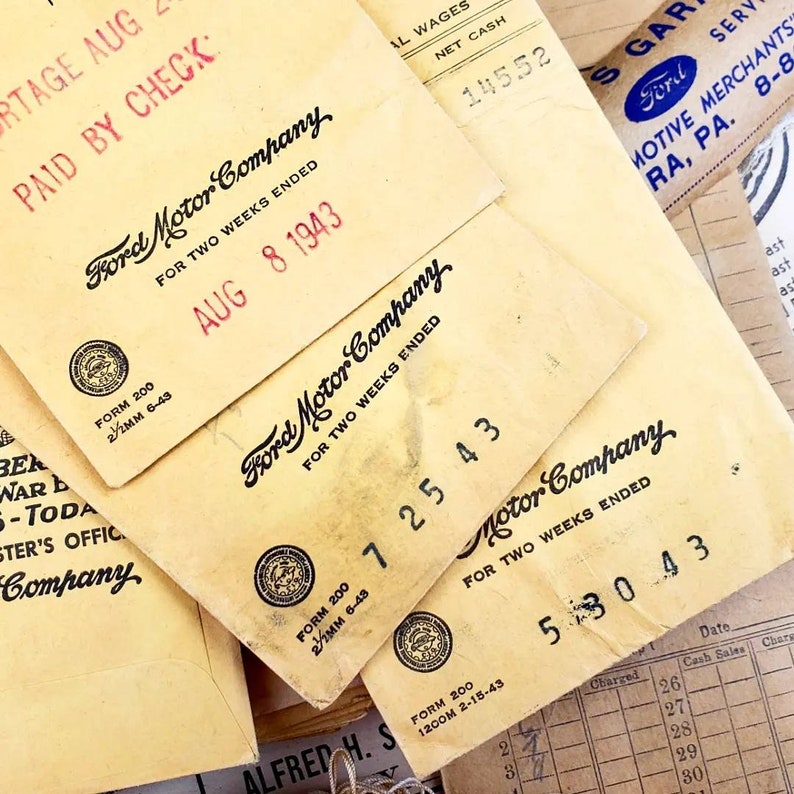 Może przedstawiać: Zbliżenie na kilka zabytkowych czek&oacute;w wypłaty Ford Motor Company z sierpnia 1943 roku. Czeki są zż&oacute;łkłe od czasu i mają logo firmy oraz tekst "Na dwa tygodnie zakończone" wydrukowany na nich.
