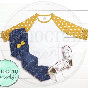 May include: A white long-sleeved shirt with mustard yellow polka dot sleeves, paired with dark blue denim jeans, a yellow bow, and white sneakers. The image includes the text "Monogram Moments".