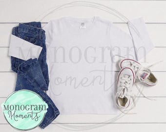 Puede incluir: Una camiseta blanca de manga larga con un par de pantalones vaqueros azules y zapatillas blancas. La camiseta está en blanco y lista para personalizar.