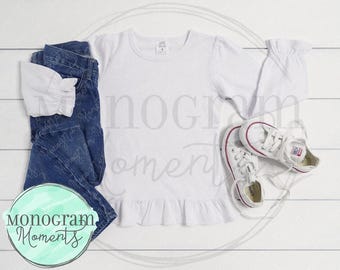 Puede incluir: Camiseta blanca de manga larga con un dobladillo con volantes, jeans azules y un par de zapatillas blancas. La camiseta tiene una pequeña etiqueta en la parte delantera que dice "One Size".