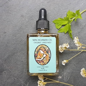May include: A small glass bottle of Macadamia Oil, cold pressed and organic unrefined. The bottle has a blue label with a drawing of a woman with long red hair and the text "COLD PRESSED PURE 15ml 0.5fl oz".