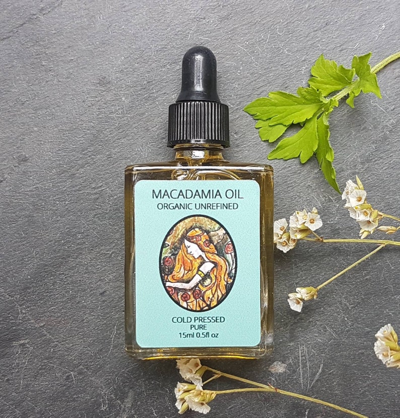 May include: A small glass bottle of Macadamia Oil, cold pressed and organic unrefined. The bottle has a blue label with a drawing of a woman with long red hair and the text "COLD PRESSED PURE 15ml 0.5fl oz".