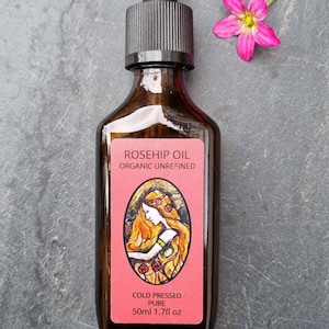 May include: A brown glass bottle with a dropper top filled with rosehip oil. The label reads "Rosehip Oil Organic Unrefined Cold Pressed Pure 50ml 1.7fl oz".